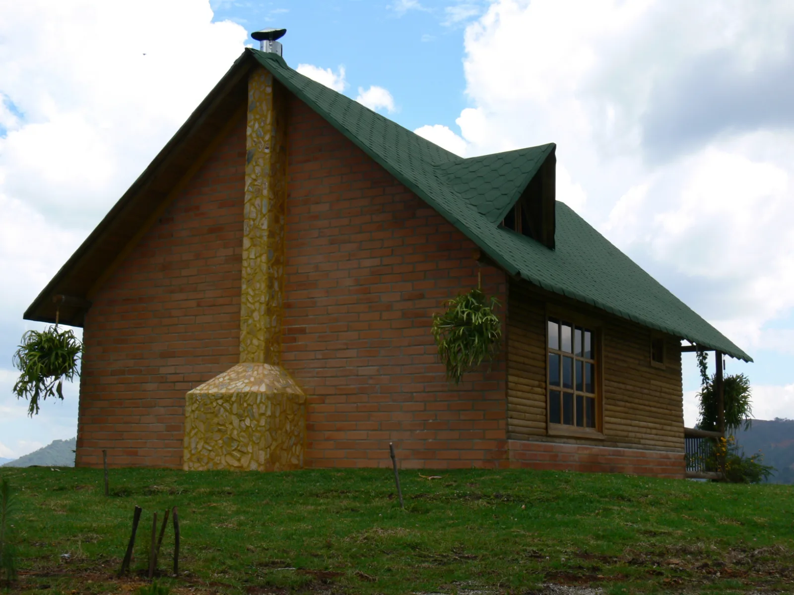 Timber cottage with a stone chimney and green roof