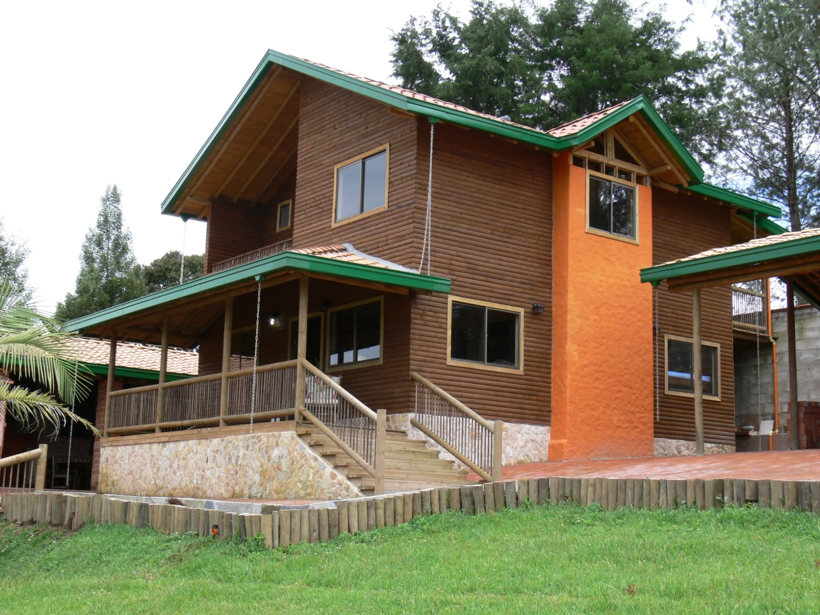 Two-storey timber cottage with green trim and a covered porch