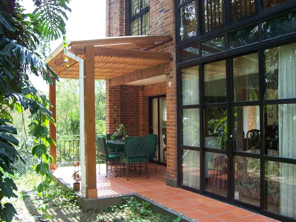 Covered patio pergola beside a brick house