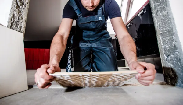 A tradesperson setting a large floor tile by hand