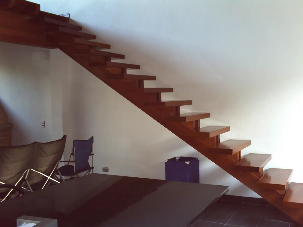 Floating wooden staircase against a white wall